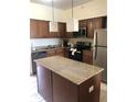 Kitchen features an island with a granite countertop, stainless steel appliances and wooden cabinets at 12527 Floridays Resort Dr # 603E, Orlando, FL 32821