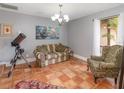 Cozy living room with terra-cotta floors, a comfortable couch, and a large window that lets in natural light at 490 Burnt Tree Ln, Apopka, FL 32712