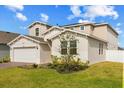 Angle view of a two-story home with manicured lawn, showing lush plants and a brick driveway at 1103 Silo Dr, St Cloud, FL 34771