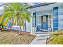 Elegant blue front door framed by sidelights, landscaping, and a mature palm tree at 1111 Lynx Trl, Winter Springs, FL 32708