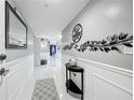 Bright hallway with a white wainscoting and a decorative mirror and floral wall art at 1150 Carmel Cir # 301, Casselberry, FL 32707