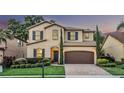 Charming two-story home featuring manicured landscaping, a brick driveway, and a two-car garage at 1558 Terra Verde Way, Ocoee, FL 34761