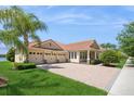 Elegant home featuring a three-car garage, red tile roof, and well-maintained landscaping with a palm tree at 15698 Marina Bay Dr, Winter Garden, FL 34787