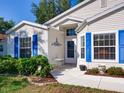 Charming entrance with blue shutters, a small seating area, and decorative landscaping at 25307 La Grange Ct, Leesburg, FL 34748