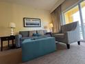 Relaxing living room showcases a plush sofa, houndstooth armchair, lamps, and large picture window at 8125 Resort Village Dr # 51006, Orlando, FL 32821