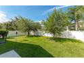 Spacious backyard featuring lush green grass, a basketball hoop, and a white fence for added privacy at 16843 Cedar Run Dr, Orlando, FL 32828
