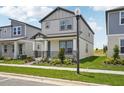 Two-story home featuring a covered front porch, manicured lawn, and a light gray exterior with a view at 5133 Passion Flower Way, Winter Garden, FL 34787