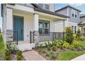 Covered front porch with brick accents, stylish railing, garden and a painted front door on a two-story home at 5133 Passion Flower Way, Winter Garden, FL 34787