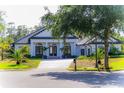 Beautiful white home featuring a circular driveway, black trim, manicured lawn, and lush landscaping at 6550 Cartmel Ln, Windermere, FL 34786