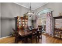 Elegant dining room featuring a wooden table, stylish chandelier, and large window with patterned curtains at 889 Kensington Gardens Ct, Oviedo, FL 32765