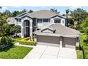 Elegant two-story home featuring a three-car garage, manicured lawn, and carefully arranged landscaping at 10033 Hart Branch Cir, Orlando, FL 32832