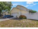 Side view of home with two-car garage, white privacy fence, and blooming bushes at 1188 Foxforrest Cir, Apopka, FL 32712