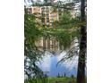 Lake view of the multi-story building reflecting in the water through the trees at 12539 Floridays Resort Dr Dr # 208D, Orlando, FL 32821