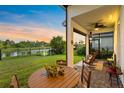 Relaxing covered back patio with view of the lake, lush lawn, and outdoor seating area at 14749 Walcott Ave, Orlando, FL 32827