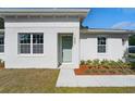 Close-up of a modern home's entry with a light-green door and decorative landscaping at 1620 Haddock St, St Cloud, FL 34771