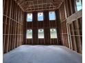 An unfinished room with exposed wood framing and multiple windows at 22117 Amberbush Court, Mount Dora, FL 32757