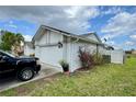Side view of a home featuring an attached two-car garage and manicured landscaping at 2673 Dixie Ln, Kissimmee, FL 34744