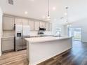 Bright kitchen features gray cabinets, stainless appliances, an island with a sink, and modern lighting at 408 Lily Ln, Davenport, FL 33837