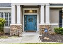 Close-up of a stylish blue front door framed by stone pillars and a welcoming wreath at 413 Macchi Ave, Oakland, FL 34787