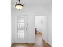 Bright entryway features a glass-paneled front door, hardwood floors, and access to the half-bathroom at 456 Harbor Winds Ct, Winter Springs, FL 32708