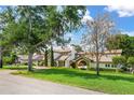 Expansive home featuring a manicured lawn, mature trees, and a charming facade at 645 Manor Rd, Maitland, FL 32751