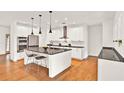 Modern kitchen features stainless appliances, granite counters, island with bar seating, and stylish pendant lighting at 10452 Log House Rd, Clermont, FL 34711