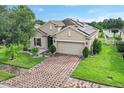 Attractive single-story home with brick driveway and solar panels, framed by manicured landscaping and green lawn at 528 Bridgeford Crossing Blvd, Davenport, FL 33837