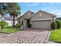 Inviting home with brick driveway and attached two-car garage framed by manicured landscaping and a shady tree at 528 Bridgeford Crossing Blvd, Davenport, FL 33837