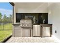 Outdoor kitchen with stainless steel grill, granite countertop, and refrigerator at 10002 Brown Burrow St, Orlando, FL 32829