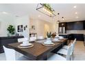 Open-concept dining and living area with a wooden dining table, white chairs, and a view of the kitchen at 1013 Leader St, Davenport, FL 33896