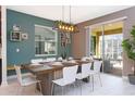 Inviting dining room featuring a large rustic table, white chairs, modern light fixture and sliding glass doors at 1013 Leader St, Davenport, FL 33896