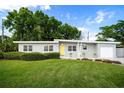 Charming one-story home with a well-manicured lawn, minimalist yard art, and a bright yellow front door at 2707 Chelsea St, Orlando, FL 32803