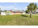 Expansive backyard with a well-kept lawn, white fence, and a mature palm tree at 2945 Juniper Dr, Edgewater, FL 32141