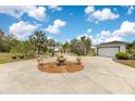 Long driveway leading to a spacious home and detached garage, surrounded by lush greenery and palm trees at 6816 Greengrove Blvd, Clermont, FL 34714