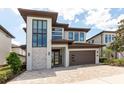 Contemporary two-story home with a brick driveway and modern architectural details at 7928 Jacks Club Dr, Kissimmee, FL 34747