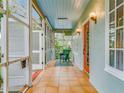 Sun porch with tile flooring, sky blue ceiling, green wicker chair and open louvered doors at 811 Laurel Ave, Orlando, FL 32803