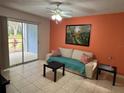 Bright living room featuring sliding glass doors to a patio, neutral sofa, and orange accent wall at 2524 Grassy Point Dr # 104, Lake Mary, FL 32746