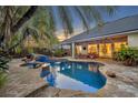 Gorgeous backyard pool with stone features, a hot tub, and serene lighting at twilight at 1130 Roxboro Rd, Longwood, FL 32750