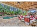 Tranquil covered patio with an adjacent pool, spa, and lush landscaping, perfect for entertaining at 1130 Roxboro Rd, Longwood, FL 32750