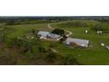 Aerial of a property with multiple buildings, including a barn, surrounded by green fields and mature trees at 11320 Montevista Rd, Clermont, FL 34711