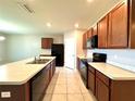 Spacious kitchen showcasing dark wood cabinetry, a black appliance suite, and tiled flooring at 133 Grove Branch Rd, Winter Haven, FL 33880