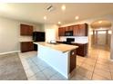Well-lit kitchen equipped with sleek black appliances, dark wood cabinets and a central island at 133 Grove Branch Rd, Winter Haven, FL 33880