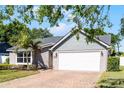 Charming single-story home featuring a gray exterior, well-maintained landscaping, and a brick-paved driveway leading to a two-car garage at 150 Dempsey Way, Orlando, FL 32835