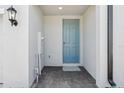 View of the home's entryway, featuring a blue door and gray tiled floor at 16443 Bird Of Paradise Ave, Clermont, FL 34714
