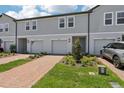 New townhome exteriors featuring a two-car garage, neutral colors, and a brick paved driveway at 16443 Bird Of Paradise Ave, Clermont, FL 34714