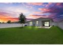 Spacious backyard with a white fence, green lawn, and a cozy fire pit area with pavers at 2731 Rowan St, Tavares, FL 32778