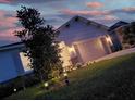 Single-story home's front exterior at dusk, featuring a two-car garage and illuminated landscaping at 2731 Rowan St, Tavares, FL 32778