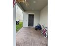 Covered front entrance with a brick-paved walkway, modern door, and bikes at 2753 Monticello Way, Kissimmee, FL 34741