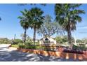 Landscaped community entrance featuring the 'Hidden Oaks' sign and beautiful palm trees against a clear blue sky at 3254 Oak Lake Pl # 137, Winter Park, FL 32792