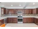 Spacious kitchen with stainless steel appliances, tile backsplash, and dark wood cabinets at 3823 Martin St, Orlando, FL 32806